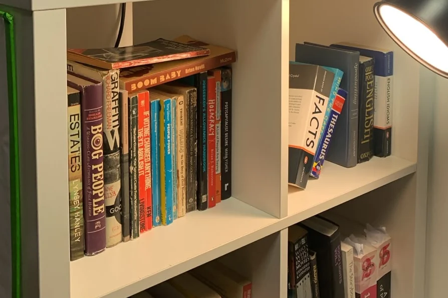 The studio’s bookshelves under a reading lamp